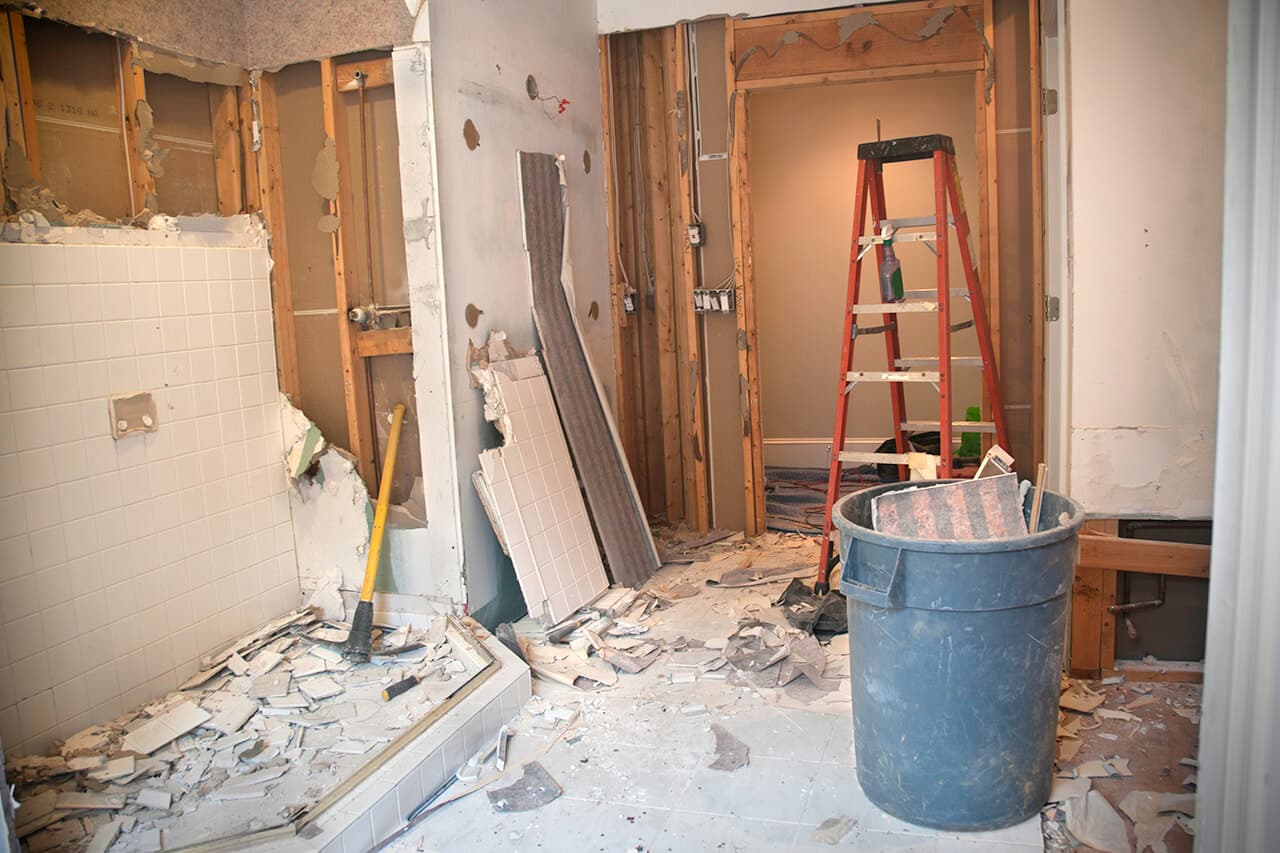 Interior demolition of bathroom with sledgehammer and debris removal